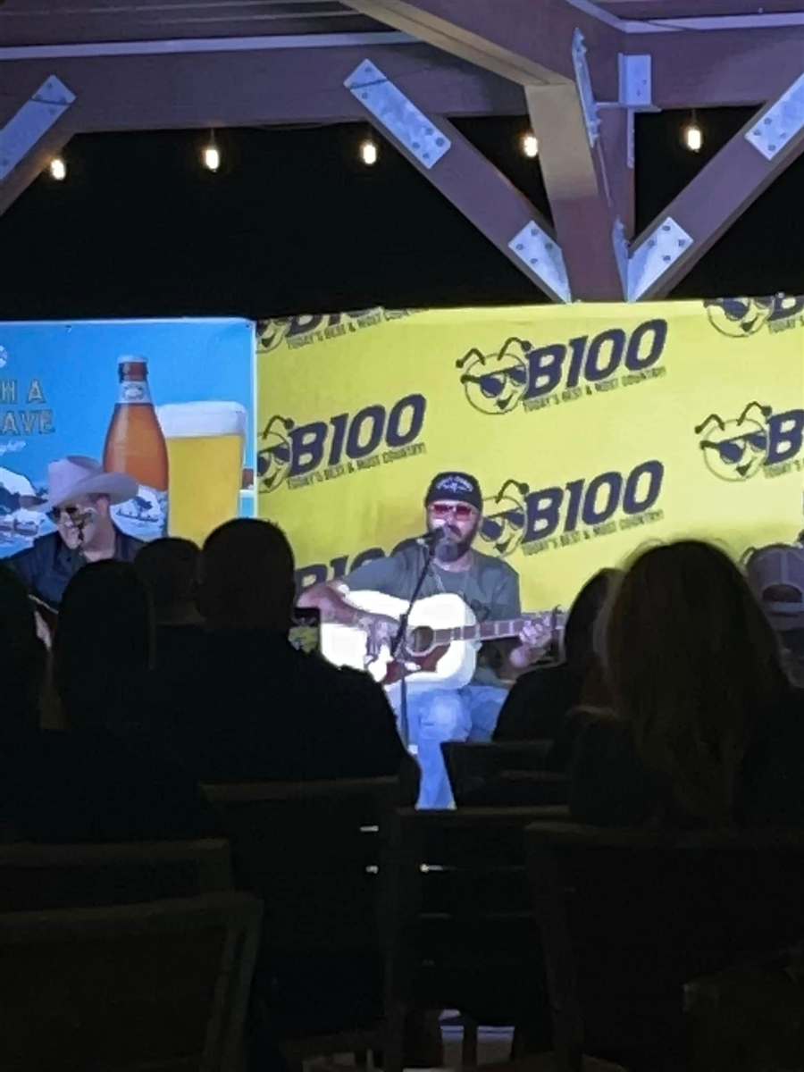 B100 live remote broadcast — performer on stage in front of a B100 banner